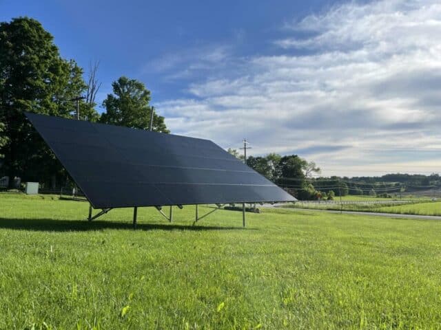 Solar panel installation in a lush green field, part of Barrett Paving's Clayville Goes Green project.