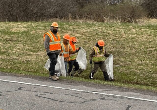 Barrett Paving northeast division employees collect litter along a roadside, celebrating Earth Day in New York.