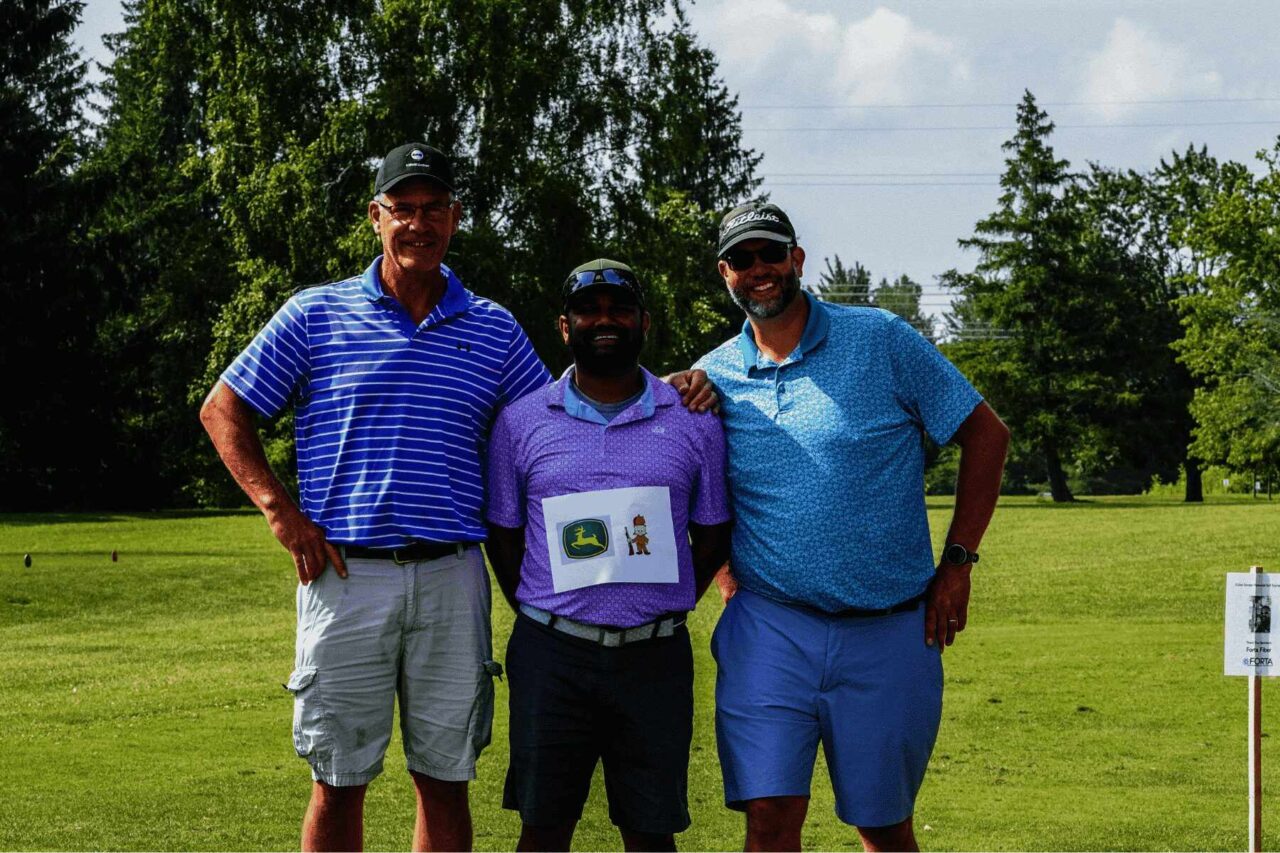 Three men smiling on a golf course during the Cullen Gorden Memorial Golf Tournament hosted by Barrett Paving.