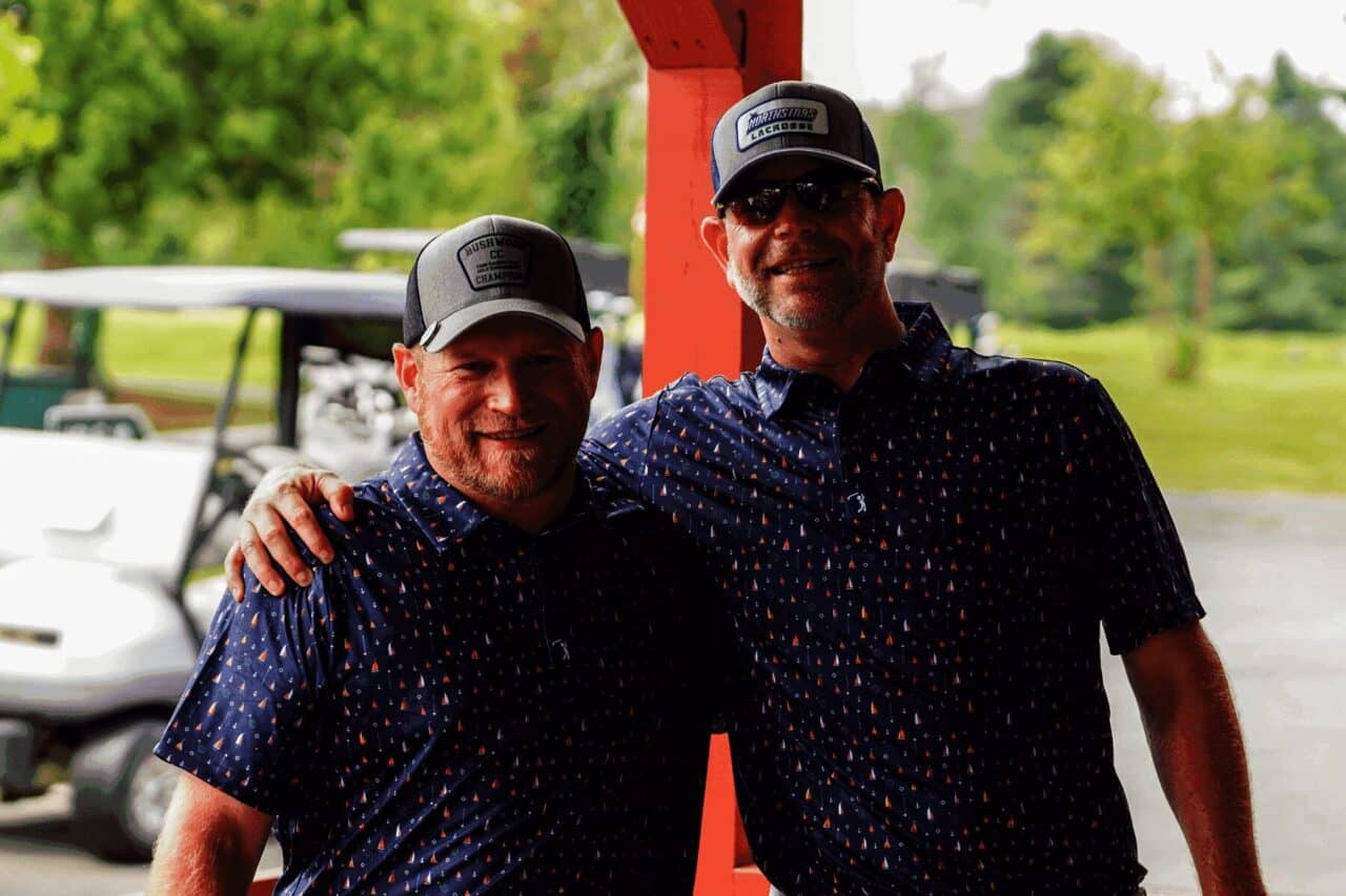 Two men in matching golf shirts and hats smile at the Cullen Gorden Memorial Golf Tournament.