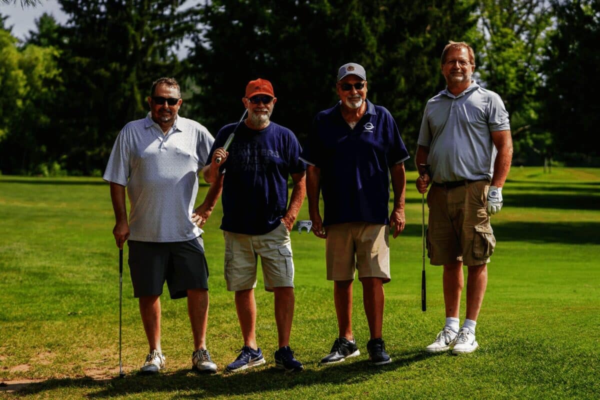 Four golfers stand on a green during the Cullen Gorden Memorial Golf Tournament hosted by Barrett Paving.