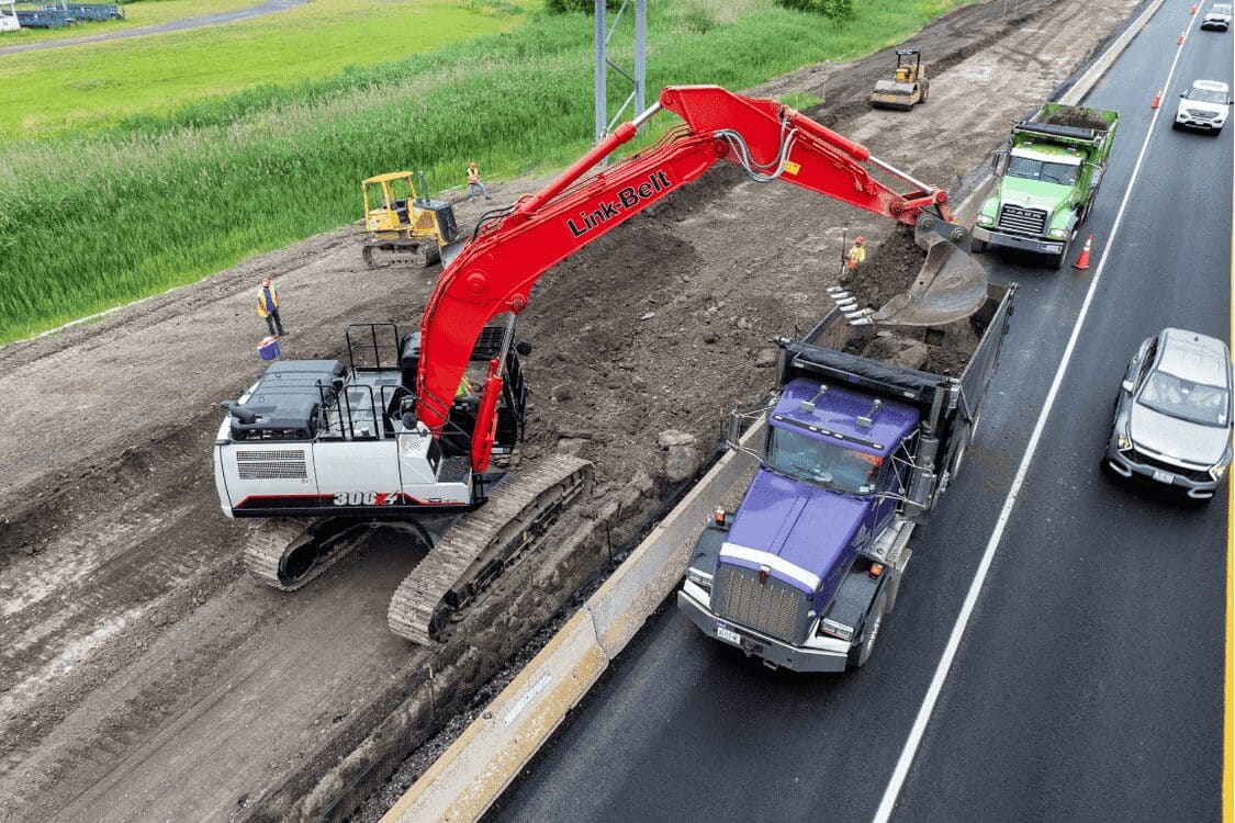 Excavator and trucks at work on NY Route 695 reconstruction, part of Barrett Paving project highlight.
